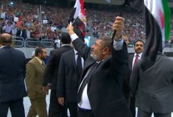 الرئيس مرسي يحيي الحضور رافعًا علمي مصر وسوريا بإستاد القاهرة