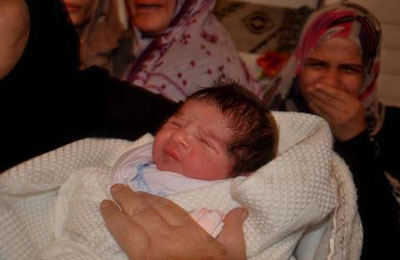 أمٌ فلسطينية تودِّع شهيدًا وتستقبل مولودًا جديدًا