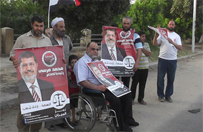 معوق يتحدى إعاقته ويشارك بأطول سلسلة بشرية لدعم د. مرسي